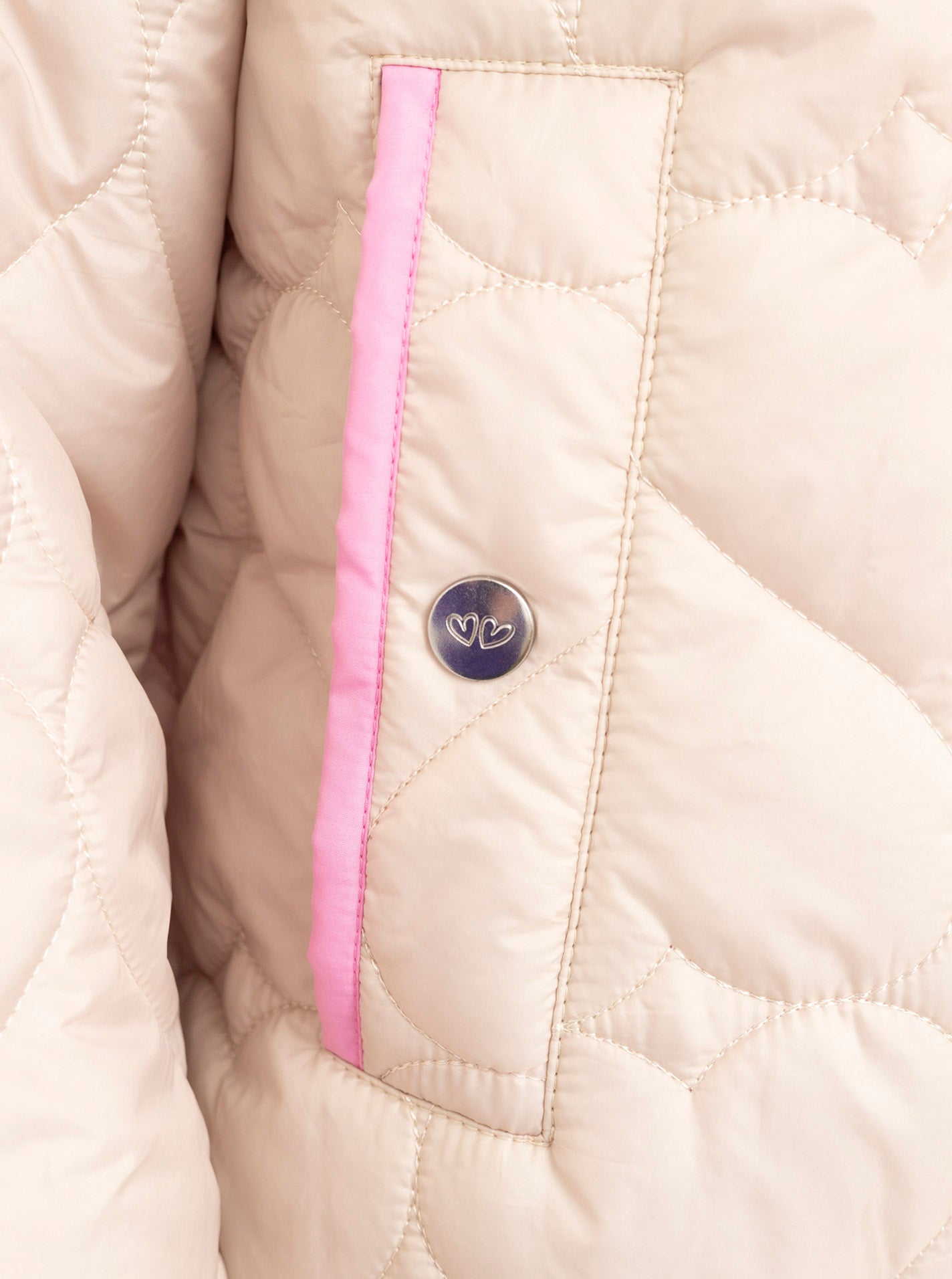 Zwillingsherz Stepp-Bomberjacke Be Happy in Hellbeige, Detailansicht der Tasche mit Herz-Steppung und pinken Akzenten