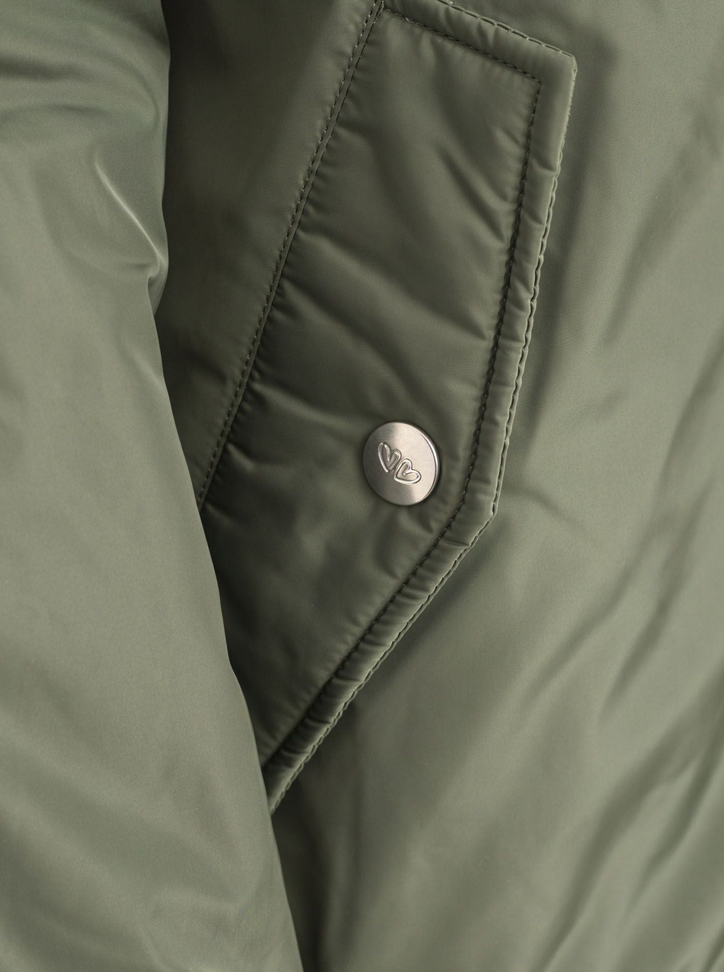 Zwillingsherz Bomberjacke Wild at Heart in Khaki, Detailansicht der Tasche mit Leo-Akzent und Druckknopfleiste